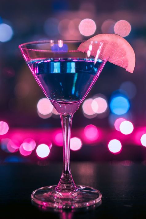 Martini glass filled with glimmering liquid, with a citrus wedge on top. There are multi-colored sparkling lights all around. Kiss Cocktail, Neon Food, Travel Planner Template, Raspberry Vodka, Bachelorette Party Weekend, Cocktail Photography, Cocktail And Mocktail, Holiday Drink, Bachelorette Trip