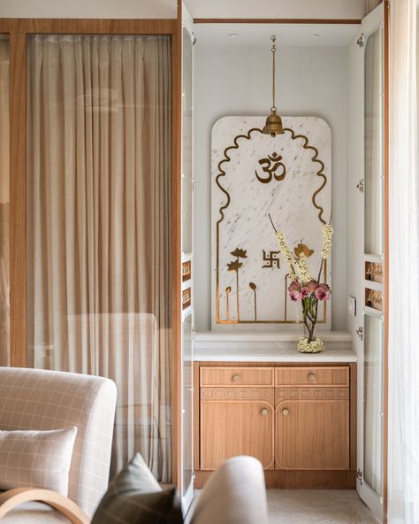 The mandir space of the Kābu home ❤️ When we brought down a bedroom wall to allow for more light in the living-dining spaces, we created a small space for the mandir. Minimal just like the rest of the home but warm and elegant , we conceptualised a marble back panel here with brass inlaid lotuses and religious motifs. A fluted glass door with strings of bells in a cutout in the middle, adds to the pious charm 🥰 . Photo credit: @nayansoni21 . . #studioipsa mandir | puja room | interior... Temple For Small Space, Puja Space In Living Room, Pooja Space Design, Pooja Room Small Space, Mandir Design In Bedroom, Minimal Pooja Unit, Interior Mandir Design, Marble Puja Mandir, Modern Home Mandir Designs