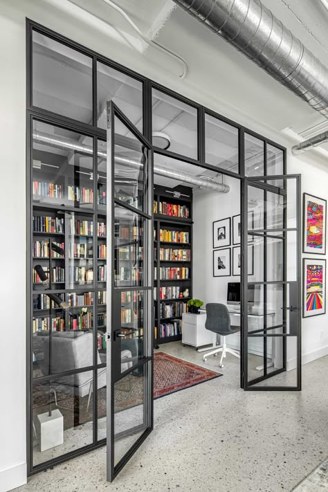 A modern home library enclosed behind a glass wall, has custom black shelving and a ladder to reach the upper shelves. Space Dividers Office, Library And Office Room, Modern Library Design Home, Office Divider Ideas, Shared Office Space Ideas Home, Home Gallery Design, Library Design Home, Home Library Aesthetic, Glass Home Office