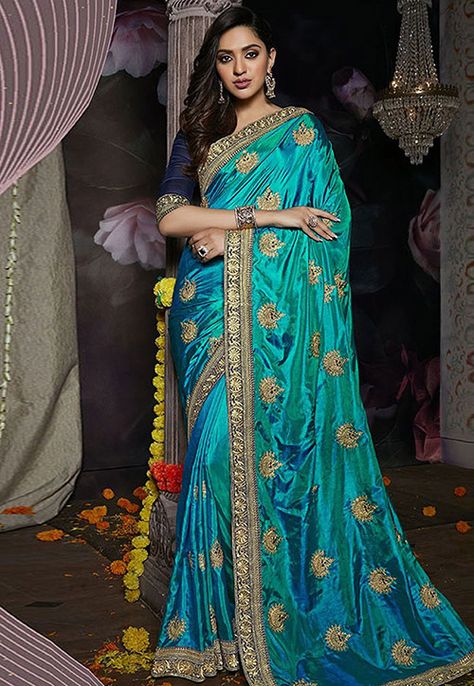 Saree embroidery designs can turn even the most modest-looking garment into an aristocratic outfit. It is a magical art form that requires a great deal of experience and craftsmanship to bring an image to life. The handwoven embroidered sarees take her over a month to create the elaborate and highly detailed patterns. Turquoise Blue Saree, Blue Colour Saree, Turquoise Saree, Blue Sari, Gold Saree, Classic Saree, Party Wear Sarees Online, Indian Designer Sarees, Saree Embroidery Design