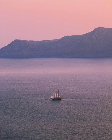 sailing boat and pink pastel sea at sunset with big volcanic cliffs in the backdrop in santorini island greece Sunset Santorini, Sky Islands, Sea At Sunset, Sky Island, Pastel Sunset, Pink Sea, Sailing Boat, Greek Island, Pink Sky