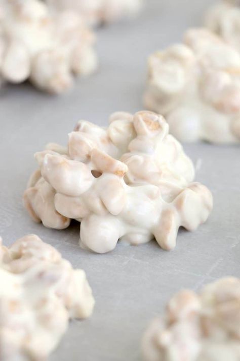 white chocolate peanut cluster shown on parchment paper. White Chocolate Peanut Butter Crispies, White Chocolate Peanut Clusters Crock Pot Candy, White Chocolate Peanut Butter Marshmallow Clusters, White Chocolate Cashew Clusters, Snacks With White Chocolate, White Chocolate Pecan Clusters, White Chocolate Nut Clusters, White Melting Chocolate Recipes, White Chocolate Clusters