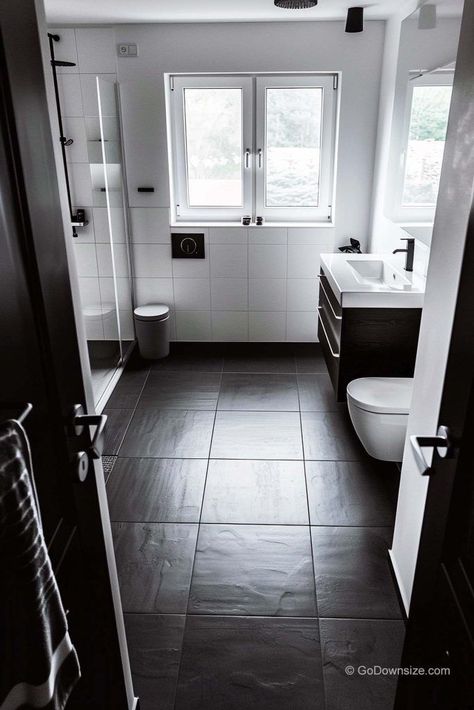 This bathroom is all about keeping things sleek and simple. The crisp white walls are the perfect contrast to the dark flooring. Bathroom Black Floor White Walls, Small Bathroom Dark Floor, White Square Tile Bathroom, Bathrooms With Black Floors, Dark Tile Bathroom Floor, Bathroom Dark Floor, Dark Bathroom Floor Tile, Bathroom Black Floor, Dark Floor Bathroom