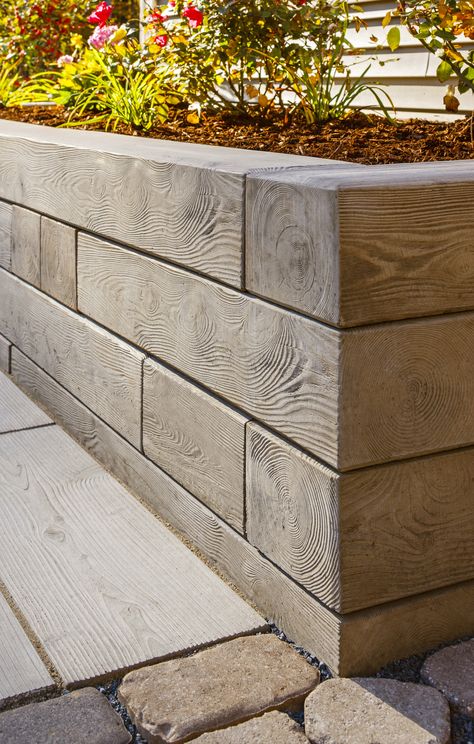 This retaining wall design is inspired by our Borealis wall. The Borealis wall takes the aesthetic of natural wood and turns it into a more durable concrete option. Embrace nature in all its beauty, in a maintenance-free way. From fire pits to flower beds, this wall adds character and warmth to any outdoor space. Offered in three alluring colors, this product complements any outdoor space! Check out our website to shop the look! Sleeper Retaining Wall, Wood Retaining Wall, Backyard Retaining Walls, Retaining Wall Design, Retaining Wall Blocks, Fireplace Stone, Garden Retaining Wall, Concrete Retaining Walls, Wall Fireplace