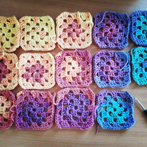 Fourteen granny squares, crocheted in colour changing yarn sitting on a wooden table beside a crochet hook and scissors. Granny Square Ombre Yarn, Sunset Granny Square, Gradient Yarn Crochet, Crochet Dinosaur Hat, Crochet Granny Squares, Colourful Crochet, Unicorn Hat, Bee Toys, Ombre Yarn