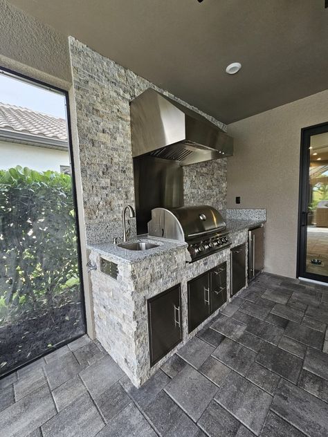 Key Features of This Outdoor Kitchen This 9’6” outdoor kitchen was built in the uber popular Lazio floorplan by Taylor Morrison in the Esplanade Lake Club in Fort Myers.  It has, in our opinion, the most useful combination of components, which are the grill (and hood), sink, fridge and trash/recycle bin.  If you are looking… Read more » Outdoor Kitchen On Porch, Built In Outdoor Kitchen, Craftsman Outdoor Kitchen, Outdoor Kitchen Refrigerator, Outdoor Kitchen Appliances Built Ins, Outdoor Kitchen Griddle Built Ins, Stacked Stone Backsplash, Outdoor Kitchen With Full Size Fridge, Compact Kitchen Design