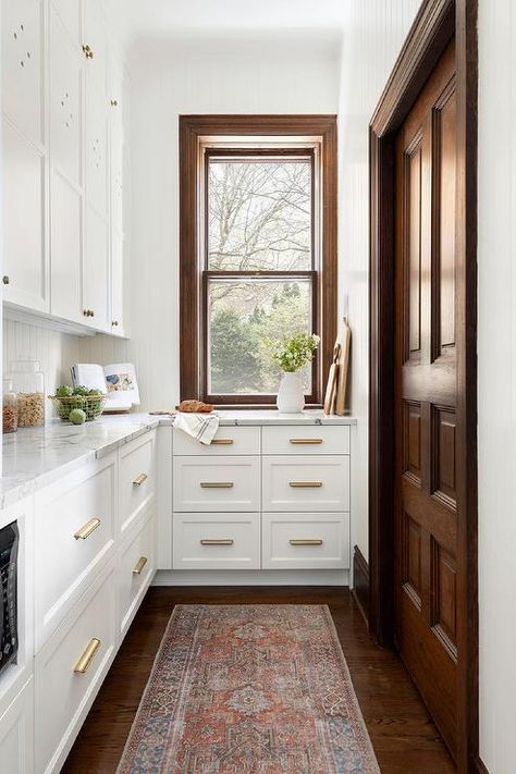 White butlers pantry designed with a brown oak door contrasting white cabinets with brushed brass vintage pulls and marble-like countertops. Traditional Kitchen Renovation, Dark Wood Trim, Long Kitchen, Dark Wood Floors, Pantry Design, Wood Trim, Decor Minimalist, Traditional Interior, Historic Home