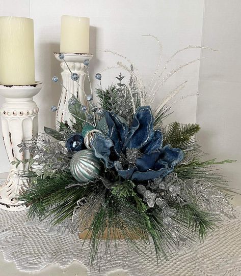 Blue magnolia centerpiece done in blue & silver with Holiday greens in a rustic wood box. #decor #magnolia #blue #centerpieces #xmas #xmasdecor #rustic #whimsical #holiday #holidaydecorating Blue And Silver Christmas Centerpieces, Winter Wedding Centerpieces Diy, Wood Box Decor, Magnolia Centerpiece, Blue Magnolia, Installation Ideas, Winter Floral Arrangements, Blue Winter Wedding, Winter Wedding Centerpieces