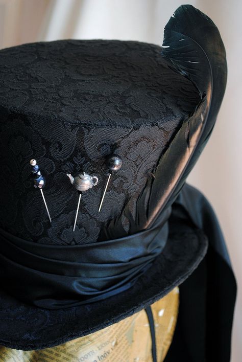 "A total black Mad Hatter ladies top hat to match the darkest Alice in Wonderland inspired costumes! This glorious hat is covered with a wonderful black brocade fabric. It is embellished with a long black taffeta train that goes around the brim and falls luxuriously at the back. The hat wouldn't be complete without some \"mad hatter\" details! A black duck feather, three unique hat pins and the signature 10/6 tag! Cause around here it's always tea-time! Fully lined with satin. Attaches with a th How To Make Mad Hatter Hat, Gothic Top Hat, Top Hat Designs, Top Hat Character Design, Top Hat Aesthetic, Mad Hatter Inspired Outfit, Gothic Mad Hatter, Wedding Top Hat, Mad Hatter Cosplay