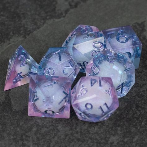 Fae magic was as difficult to understand as the Fae themselves. It seemed to exist by its own rules.Beautiful, clear pink and light blue dice with a shimmering liquid core inside. The dice shimmer magically when shaken. Note that while the pictures are unedited, the color really pops because of the dark background. You'll probably find them less vibrant in normal light.Each set contains the standard 7 roleplaying dice - d4, d6, d8 d10, d10 in 10's, d12, and the classic d20.Please keep in mind th Liquid Core Dice, Dnd Dice Aesthetic, D&d Dice, Dice Inspiration, Dice Aesthetic, Fae Magic, Dice Art, Cool Dnd Dice, Pretty Dice