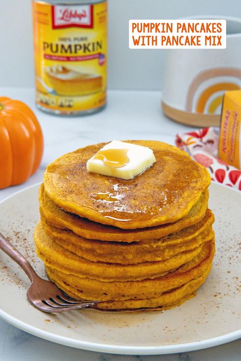 Head on view of a stack of pumpkin pancakes topped with a pat of butter with pumpkin, can of pumpkin puree, mug, and box of pancake mix in background and recipe title at top. Pumpkin Pancakes With Krusteaz, Pumpkin Pancakes With Pancake Mix Recipe, Pumpkin Pancakes With Mix Easy, Boxed Pancake Mix Recipe, Pumpkin Buttermilk Pancakes, Pumpkin Pancake Mix, Pumpkin Oatmeal Pancakes, Pumpkin Pancakes Recipe, Pumpkin Pie Pancakes