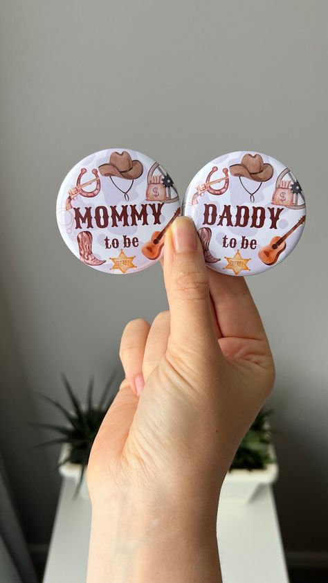 - Cowboy Neutral Baby Shower Pins - AlinaCraftStudioShop presents to your attention Mommy to be and Daddy to be Little Cowboy themed badges in brown and green colors. They're perfect as a gift for welcoming a new baby girl or boy, celebrating a gender reveal and more! Beige buttons can be a perfect addition to your pregnancy announcements and help to create a memory from this event for you and your family!  MATERIALS and SIZE: The pins are handmade, have metal base and plastic back, paper cutout Broncs Or Barrels Gender Reveal, Bulls Or Barrels Gender Reveal, Earthy Gender Reveal, Cowboy Themed Gender Reveal Ideas, Country Gender Reveal Ideas For Party, Gender Reveal Ideas For Party Western, Gender Reveal Ideas Cowboy Or Cowgirl, Gender Reveal Western Theme, Cowboy Or Cowgirl Gender Reveal Ideas