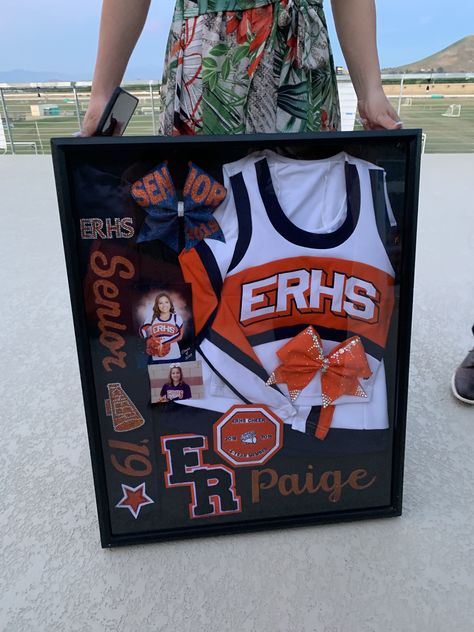 Senior Cheer Boxes Ideas, Framed Cheer Uniform, Senior Cheer Shadow Box Ideas, Cheer Shout Out Ideas, Cheerleader Shadow Box Ideas, Cheer Camp Crafts For Kids, Cheer Wall Ideas, Senior Night Baskets Cheer, Cheer Team Themes