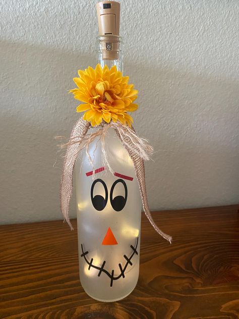 Light up your fall decor with a whimsical scarecrow lighted wine bottle.  The frosted bottle features an adorable scarecrow face glowing warmly with LED lights inside.  Perfect for a rustic touch to you fall celebrations.  Makes a cute centerpiece or a thoughtful gift for your favorite fall enthusiast. Halloween Wine Bottles Diy, Halloween Wine Bottle Crafts, Halloween Wine Bottles, Face Glowing, Glass Spider, Scarecrow Face, Spooky October, Idea For Halloween, Wine Glass Designs