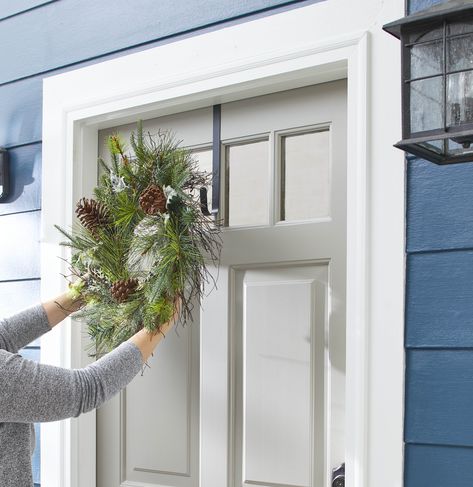 Hanging an evergreen wreath on a gray front door Wreath On Door, Double Door Wreath, Double Wreath, Hanging Wreaths, Wreath Hook, Wreath Holder, Double Door Wreaths, Outdoor Wreath, Moss Wreath