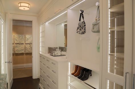 Narrow walk-in closet features Ralph Lauren Allen Round Flush Mount illuminating a built-in dresser situated under inset mirror next to built-in pegs used to display handbags stacked over shelves for shoes across from a built-in back with blue floral seat cushion with matching backsplash. Dresser Built In Closet, Built In Closet Dresser, Built In Shoe Shelves, In Closet Dresser, Tilted Shelves, Small Clothes Closet Organization, Narrow Walk In Closet, Small Clothes Closet, Shelves For Shoes