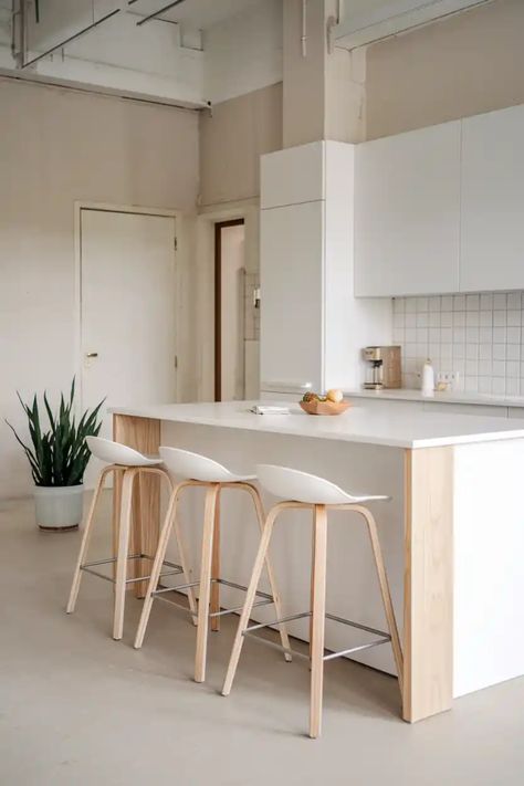 Modern kitchen with a white island, wooden bar stools, and a potted plant. Kitchen Peninsula Seating, White Bar Stools Kitchen Island, White Bar Stools Kitchen, Apartment Kitchen Island Ideas, Peninsula Seating, Scandinavian Bar, Apartment Kitchen Island, Scandinavian Bar Stool, Stools Kitchen Island