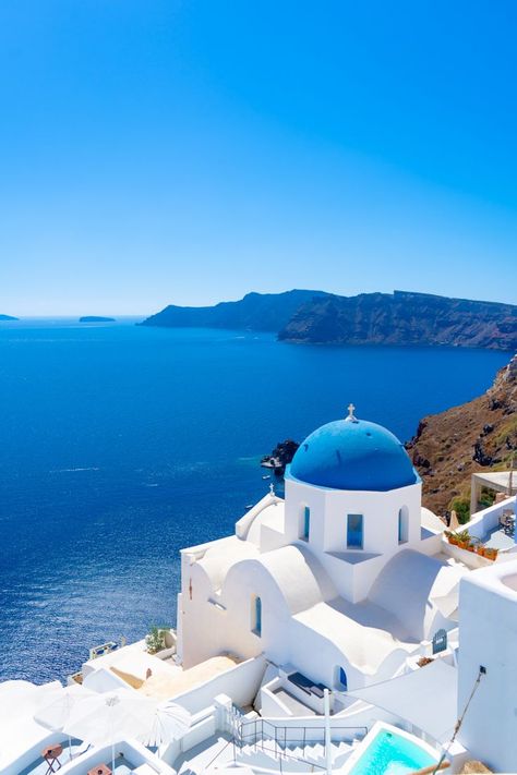 Aerial view of a blue dome church surrounded by white buildings. Blue sea and sky behind. Greece Beaches, Santorini Beach, Greece Sea, Santorini Beaches, Santorini Villas, Greece Villa, Mykonos Beaches, Greece Painting, Beach House Exterior