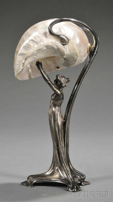 Art Nouveau Silver-plate and Mother-of-pearl Figural Lamp, Germany, late 19th/early 20th century, mark of Wurttembergische Metallwarenfabrik (WMF), the base formed as a scantily clad nymph reaching upward towards the shade formed by a large nautilus shell, bottom stamped "as WMFB I/0," ht. 13 3/4 in. Chocolate History, Art Nouveau Lighting, Architecture Art Nouveau, Art Nouveau Lamps, Lampe Art Deco, History Essay, Design Art Nouveau, Style Writing, Gold Chocolate