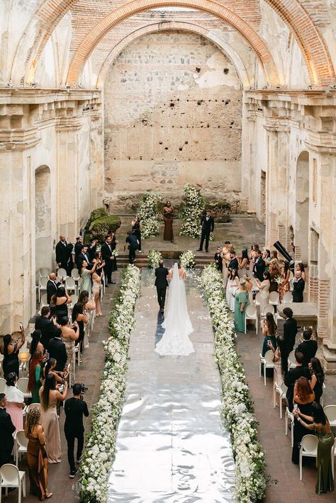 A bride with a long veil being escorted down the aisle lined with greenery and white flowers by her father toward the classic altar in a Guatemalan ruins ceremony space. Bride Walking Down Aisle, Guatemala Wedding, Spanish Style Wedding, Hacienda Wedding, Dominican Republic Wedding, South America Destinations, Earthy Wedding, Spanish Wedding, Boda Mexicana