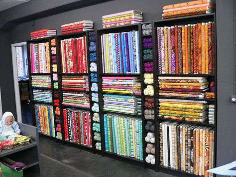 Black bookshelves for quilt shop bolt display Fabric Bolt Shelf, Quilt Shop Displays, Fabric Shop Display, Fabric Store Displays, Fabric Store Design, Thread Rack, Haberdashery Shop, Sewing Room Storage, Retail Store Interior Design