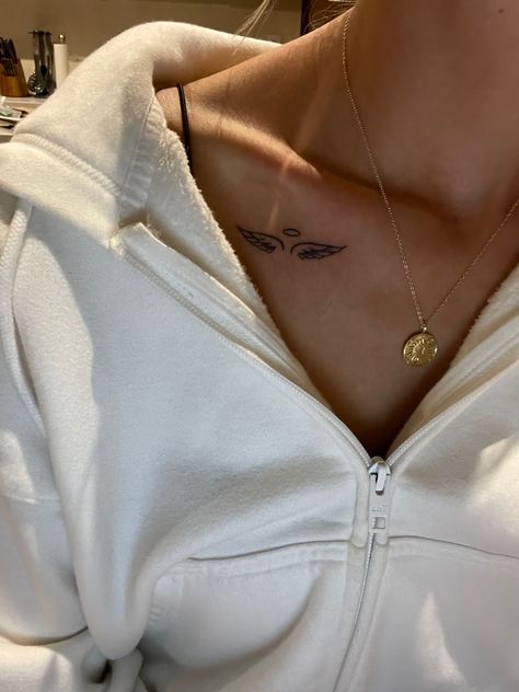 Woman wearing a white hoodie with gold necklace and tattoo Angel Wings Tattoo On Collar Bone, Angel Tattoo On Collarbone, Womens Angel Wing Tattoos, Collar Bone Tattoo Angel Wings, Angel And Halo Tattoo, Halo With Angel Wings Tattoo, Tatoos Angel Wings, Angel Wings Tattoo Above Elbow, Wings Tattoo Collar Bone