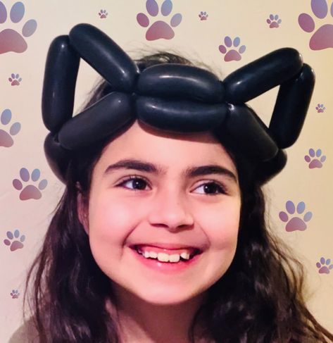 A little girl wears a black balloon hat, twisted to look like cat ears or bat ears. Balloon Animal Hat, Balloon Hats Easy, Balloon Hats How To Make, How To Make Balloon Animals Step By Step, Balloon Animal Ideas, Ballon Character, Halloween Balloon Animals, Balloon Animal Tutorial, How To Make Balloon Animals