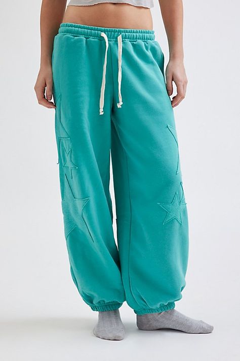 Ulta-cozy Out From Under sweatpant in a relaxed jogger style. Designed in a fleeced knit featuring a low-rise elasticated waist with drawstring detail, relaxed leg fit that cinches at the ankle and topped with star patches down the front & back of the legs. Only at Urban Outfitters. Features Out From Under Brenda star patch jogger sweatpant Slouchy lounge pant Super soft knit Low-rise elasticated waistline with drawstring tie Side pockets Star patches down the front & back of the legs Cinched el Teal Sweatpants Outfit, West Coast Outfits, Jogger Set Outfits Women, Sweatpants Design, Nike Winter Jackets, Comfy Ootd, Graphic Sweatpants, Star Patches, Cute Sweatpants