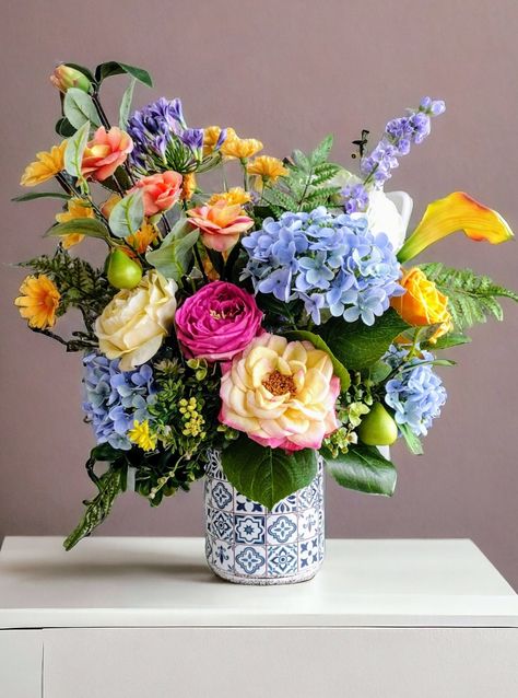 Beautiful realistic real touch and silk floral arrangement in a blue and white talavera style ceramic vase. Blue and light green real touch hydrangeas, realistic pear branches, roses, calla lilies and other wild flowers mixed with abundant foliage, arranged and nestled in a beautiful talavera style ceramic vase. It is a beautiful real like arrangement to show off in any season of the year. This arrangement is a unique piece that has been delicately handcrafted with love and dedication and represents hours of design and elaboration. At the time of purchase it will be carefully packed so that it arrives safely to its destination. I would like to mention however that should any unfortunate mishap occur during shipping, your purchase is 100% insured against any damage or loss. If you wish to s Floral Arrangements With Blue Hydrangeas, Colorful Flower Vase, Garden Style Flower Arrangement, Blue And White Ceramics, Flower Arrangements Hydrangeas, Grandparents Memorial, Natural Flower Arrangements, Blue Floral Arrangements, Hydrangea In Vase