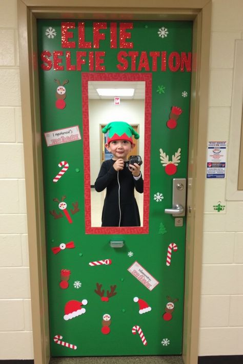 A green classroom door transformed into a festive "Elfie Selfie Station," featuring a photo frame, candy canes, and holiday-themed stickers. A young child dressed as an elf is shown taking a photo. Holiday Door Contest Decorating Ideas, Home Alone Door Decorations For School, Speech Therapy Christmas Door, Decorating Office Doors For Christmas, Door Decorating Classroom, Nurse Christmas Door, Christmas School Hallway Decorations, Office Christmas Door, Office Door Christmas Decorations Ideas