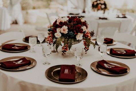 Kara and Ben incorporated beautiful burgundy details throughout their day. Their reception tables featured ivory linens, burgundy napkins, gold chargers, and breathtaking florals designed by a family friend! Burgundy Table Linens Wedding, Burgundy Themed Wedding Table Settings, Wedding Table Decorations Burgundy Blush, Cream Suit Burgundy Tie, Burgundy Flower Table Decor, Ivory And Burgundy Wedding Table, Wedding Table Settings Burgundy, Burgundy Gold Table Setting, Round Burgundy Wedding Tables