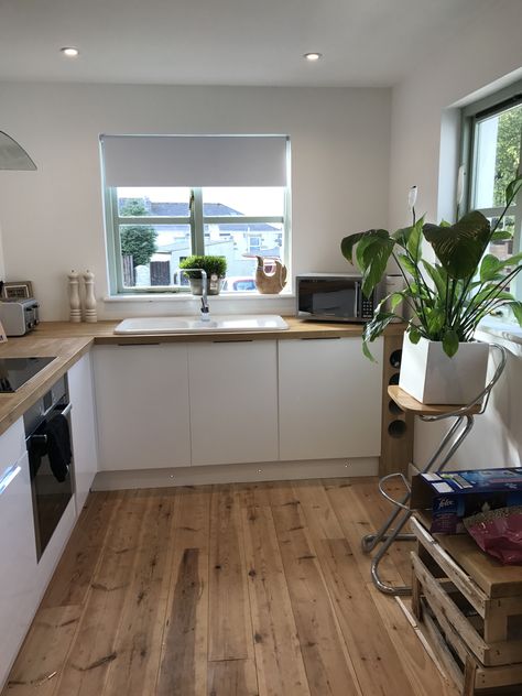 Natural kitchen theme. Ceramic white sink, oak tops, pine floorboards and gloss white doors with hidden flush handles.. and a Peace Lily to top it all off #kitchen #freshkitchen #neutralhome #floorboards #cottagekitchen #oakworktop #glosswhite White Kitchen Wooden Floor, Cream And Wood Kitchen, Slab Door Kitchen, Pine Floorboards, Kitchen Refurbishment, White Gloss Kitchen, Kitchen Revamp, White Cupboards, Wood Worktop