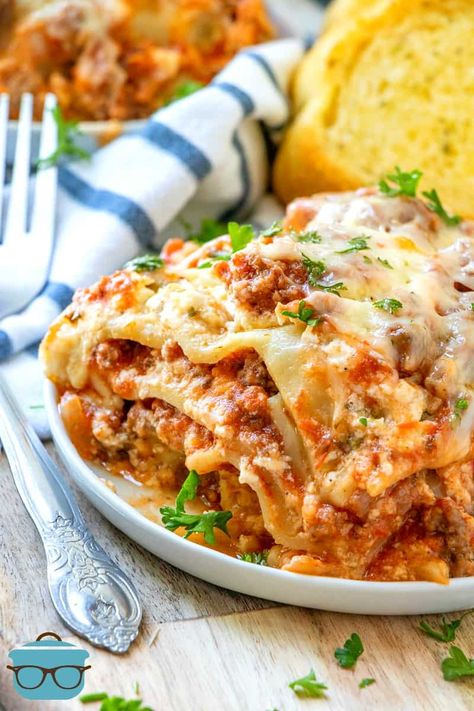 slice of crock pot lasagna on a white plate with slices of garlic bread in the background. Crock Pot Lasagna Recipe, Crockpot Lasagna, Pot Lasagna, Lasagna Noodles, Country Cook, The Country Cook, No Noodle Lasagna, Country Cooking, Crock Pot Slow Cooker