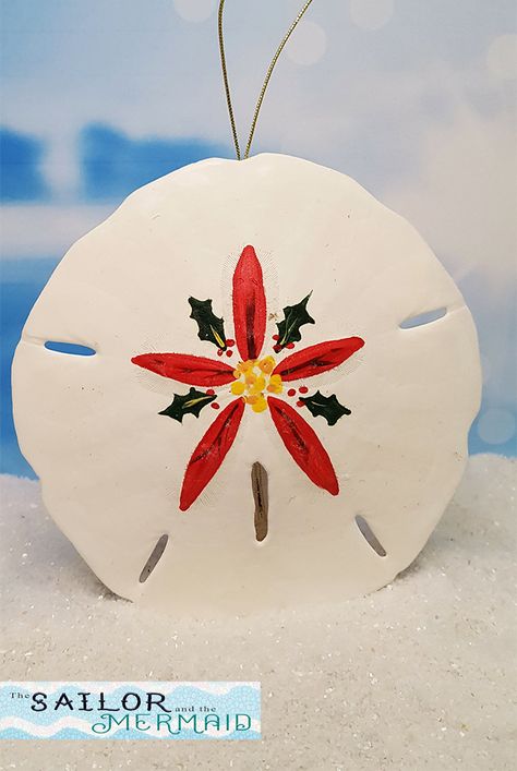 "This real Florida sand dollar has been hand painted with a bright red poinsettia surrounded by holly leaves. Use it as a holiday ornament, give as a gift to someone special, keep as a reminder of a special vacation, or simply hang on your window to enjoy year-round to bring the beach to you! We individually hand paint each of our sand dollars so that no two are exactly the same. The ornaments are finished at the top with a luminous gold cord for hanging or displaying. They measure 3.5\" to 4.5\ Painted Sand Dollars Christmas Ornaments, Painted Sand Dollars Christmas, Sand Dollar Christmas Ornaments, Oyster Angel, Sand Dollar Decor, Sand Dollar Ornaments, Florida Crafts, Pansy Art, Painted Sand Dollars