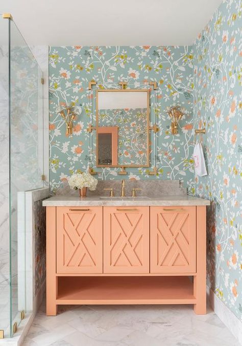 Beautiful blue and orange floral wallpaper covers the walls of this small bathroom boasting an orange sherbert washstand accented with brass hardware and a brass faucet kit fixed beneath a brass and lucite mirror flanked by brass sconces. Old Florida Decor, Bathroom With Wallpaper, Florida Bungalow, Peach Bathroom, Houston Interior Designers, Florida Decor, Orange Bathrooms, Bathroom Color Schemes, Transitional Bathroom