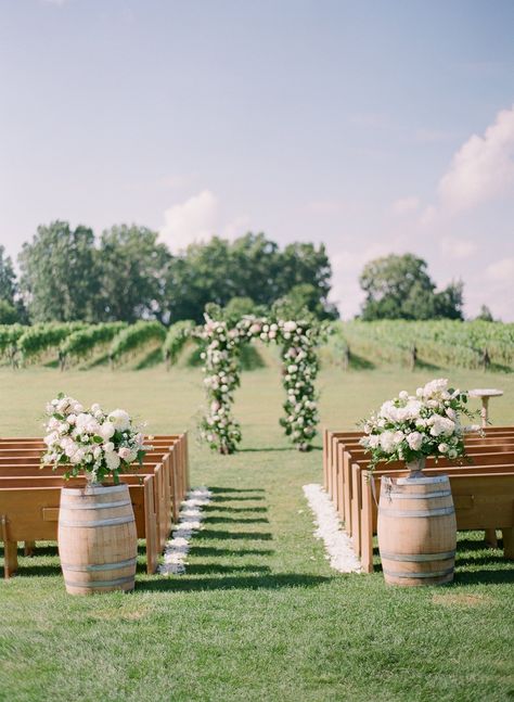 Luxury outdoor wedding at Burning Kiln Winery. Large floral arbour is a showcasing the centre of the ceremony location for a vineyard wedding | Lindsay Plank Events - Niagara and Toronto Wedding Planner. Luxury wedding floral inspiration of white and soft blush pink florals. Wine barrels with lush floral arrangements, with petal rose petals lining the ceremony aisle. Church pews overlook the ceremony location at Burning Kiln Winery for a vineyard ceremony. White and pink floral inspiration. Kontokosta Winery Wedding, Vineyard Wedding Ceremony Decor, Wine Vineyard Wedding Ceremony, Outdoor Wedding Pews, Church Pew Outdoor Wedding, Vineyard Inspired Wedding, Winery Wedding Aesthetic, Trentadue Winery Wedding, Spring Vineyard Wedding