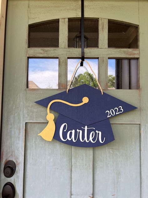 "It's time to celebrate your 2022 Graduating Senior with this Graduation Party Decoration!!  With this personalized graduation sign as your Graduation Centerpiece you can let everyone know how proud you are of your senior!  You can choose the cap color and tassel color.  If you don't see a color you need just leave it in the notes at checkout. Let's celebrate the Class of 2024! Details: *Measures approximately 18\" *Made with 1/4\" birch (background) *Lettering made with 1/8\" birch, cut on laser *Hand painted *Back side is left unpainted *Each sign comes with ribbon, burlap or wire for hanging *It's recommended to display your sign on a covered front door or porch. *Signs are made from real wood, which means you may see wood knots, crevices and other imperfections Shipping: *All items are Graduation Decorations Cricut, Graduation Party Decor For Boys, Graduation Party For Boys, Class Party Decoration Ideas, Graduation Wreaths For Front Door, Cricut Graduation Decorations, Graduation Centerpiece Ideas For Boys, Graduation Party Decor With Cricut, Graduation Sign Ideas