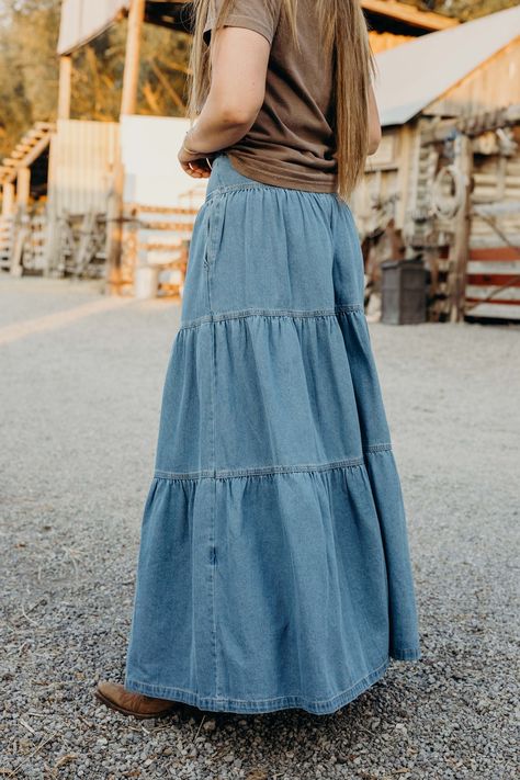 Get ready to twirl in style with The Lodonna Skirt. This light wash, tiered maxi skirt is made from soft denim and features side pockets for convenience. The elastic waistband provides a comfortable fit, while the western style adds a touch of flair. Haylee is wearing size small paired with the Horsin Around Tee and Parker Cardigan Tiered Denim Skirt Outfit, Tiered Denim Skirt, Jeans Into Skirt, Quilt Skirt, Diy Maxi Skirt, Long Jean Skirt, Quilted Skirt, Denim Skirt Outfits, Western Style Outfits