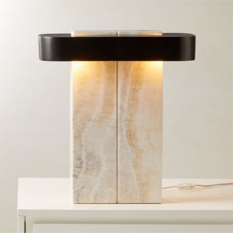 White onyx creates a modern industrial silhouette for Studio Anansi's table lamp design. A stunning juxtaposition of organic materiality and sleek black metal, the base is carved by hand from a single slab of white onyx. When lit, the stone emits a warm, soft glow. CB2 exclusive.  -Hand-carved -Designed by Studio Anansi -Solid white onyx base -Stainless steel shade with blackened finish -Variation in color and activity of onyx is to be expected; each will be unique -Accommodates four type B, E12 Marble Bistro Table, Onyx Table, Cement Table, Lamps Desk, Marble Furniture, Marble Lamp, Marble Table Lamp, White Onyx, Contemporary Lamps