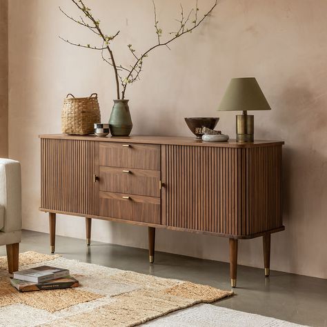 Our mid-century inspired Byron Sideboard is a vintage-style storage and display unit ideal for dining rooms and living spaces. Its warm walnut finish brings a timeless vintage look to your home, with two tambour slatted doors that slide open smoothly to the side, revealing adjustable glass shelving within. The sideboard features three central drawers, and is decorated with solid T-bar brass handles that match the gorgeous brass caps on the tapered legs. Our Byron collection also includes an extendable dining table, media unit, coffee table and side table. | Byron Sideboard by Atkin and Thyme, W160 x H75 cm Side Units Living Rooms, Side Boards And Buffets Living Room, Fluted Glass Sideboard, Dining Room Sideboard Decor Ideas, Sideboard Accessories, Vintage And Modern Decor Mixing, Dining Room Sideboard Styling, Sideboard Decor Ideas, Art Deco Buffet Sideboard