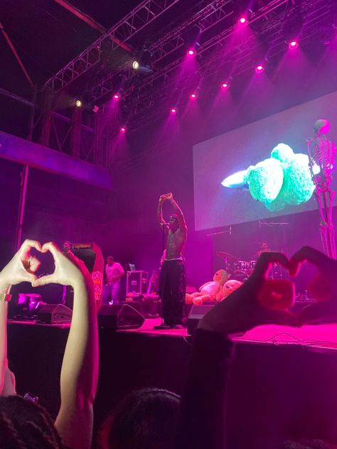 Artist Rema on a stage doing a heartshape with his fingers. Fans are doing the same back to him. There’s pink stage light. Beautiful picture and stage. Rappers On Stage, Rema Concert, Grunge 2023, Pfp Material, Spotify Playlists, Music Genres, Live Show, Man Alive, On Stage