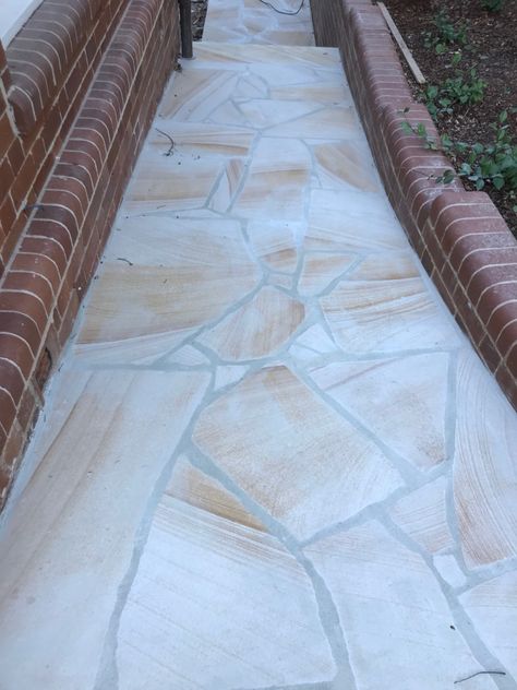 This is a style used for random shaped pieces of stone. Some stone might be more angular in shape giving a sharper, more defined look, and some stone may be more rounded in shape giving a softer feel. Crazy stone paving is all about getting the grout gaps correct. Larger grout gaps will increase the dominance of the grout in the finished job and tighter grout gaps will let the stone take prominence. Paver Garden, Sandstone Flooring, Exterior Flooring, Flagstone Pavers, Sandstone Pavers, Pavers Diy, Coastal Flooring, Garden Pavers, Pool Pavers