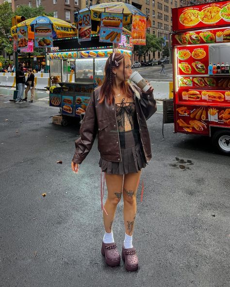 The carrousel of photos shows @sheisnevil wearing a brown outfit with heeled crocs and a ribbon hairstyle. First is a head-to-toe picture of her sipping in a Starbucks cup in the streets of New York City. Second is a close-up on her nails and crocs. Third is her standing in front of a mammoth fossil in the American Museum of Natural History. Siren Clog Crocs, Croc Heels Outfit, Crocs Heels Outfit, Siren Crocs Outfit, Brown Crocs Outfit, Crocs Outfit Fall, Crocs Siren Clogs Outfit, Siren Clog Crocs Outfit, Crocs Clogs Outfits Style