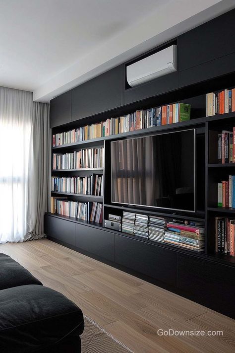 Black cabinetry and shelving create a sleek, modern look that can elevate the overall design of a room. Tv And Bookcase Wall, Black Tv Unit, Black Bookshelves, Black Cabinetry, Staircase Interior Design, Under Tv, Living Room Wall Units, Library Wall, Bookcase Wall