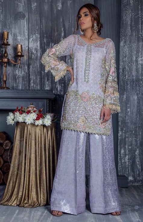 Standout in this gorgeous chiffon shirt embellished with tilla, kora dabka, sequins and pearls. It is further enhanced with floral thread embroidery. Its hemline and sleeves are beautifully decorated with golden tassels. It is beautifully coordinated with self embroidered jacquard bell bottom trousers. Pakistan Outfits, Party Dress Pakistani, Grey Party Dress, Asian Fits, Eid Fits, Kurta Ideas, Annus Abrar, Floral Thread Embroidery, Asian Attire