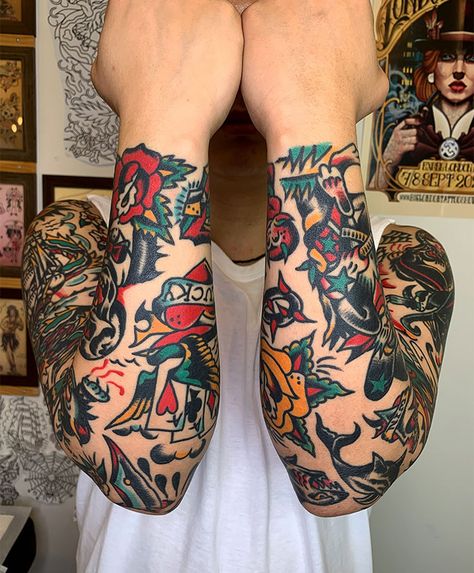 A man displaying both arms fully covered with colorful traditional-style tattoos featuring roses, playing cards, swallows, and bold outlines. Tattoo ideas for men inspired by classic Americana designs with vibrant colors and symbolic motifs. Tattoos Between Breast, Best Tattoo Ideas For Men, Aries Tattoos, Lower Arm Tattoos, Americana Tattoo, Americana Design, Traditional Style Tattoo, Traditional Tattoo Sleeve, Best Tattoo Ideas