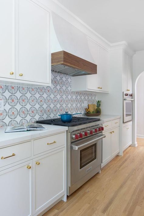 This kitchen features a modern take on Spanish style with crisp white cabinets, walls and a range hood. The bold tile backsplash creates a statement wall and coordinates with the gourmet oven's red knobs. Kitchen Full Wall Cabinets, Full Wall Cabinets, Kitchen White Cabinets, Spanish Style Tile, Spanish Style Kitchen, Bold Tile, Spanish Kitchen, Hardwood Floors In Kitchen, Dark Wood Kitchens