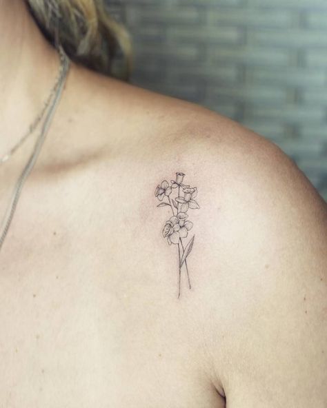 Fine line style daffodils tattoo done on the shoulder. Daffodil Tattoo Dainty, Daffodil Shoulder Tattoos For Women, Daffodil Tattoo Shoulder, Daffodil Tattoo Fine Line, Delicate Daffodil Tattoo, Pretty Daffodil Tattoo, Fine Line Daffodil Tattoo, Narcissus Flower Tattoos, Daffodil Tattoo