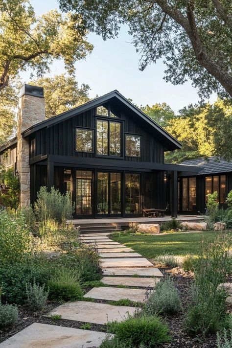 Modern barndominium house facade of black stained wood with black trim beautiful farmhouse garden landscape. Check out the coolest dark barndominium houses that combine rustic charm with modern sophistication, enhancing a living space with bold hues and sleek designs. Modern Black Barndominium, Barndominium Luxury, Black Barndominium Floor Plans, Black Ranch Style House, Dark Barndominium, Cottage Barndominium, Black Barndominium Exterior, Barndo Exterior, Unique Barndominium