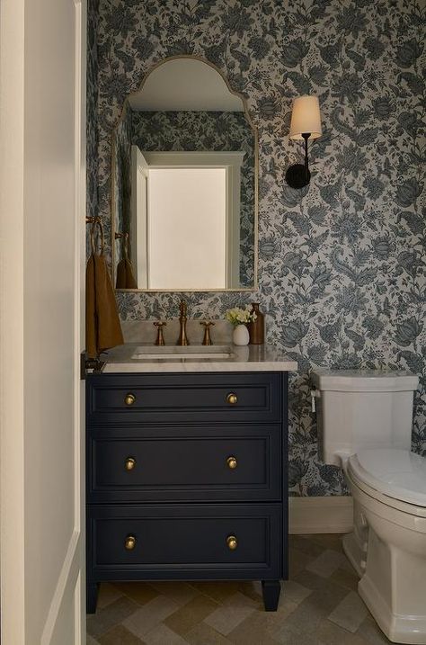 Powder room features a navy blue washstand with marble countertop and antique brass vintage style faucet under a silver leaf arch mirror mounted on white and blue botanical wallpaper. Navy Blue Powder Room Wallpaper, Navy Blue Powder Room, Grey Trellis Wallpaper, Blue Botanical Wallpaper, Blue Powder Room, Blue Velvet Couch, Wainscoting Bathroom, White Shutters, Powder Room Wallpaper